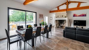 Un vaste espace dédié à la salle à manger, comprenant une grande table et des chaises, une cheminée et un téléviseur.