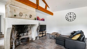 Un salon moderne avec une cheminée, un canapé en cuir noir et une grande horloge murale.