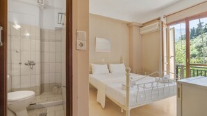 A bedroom with a bed, a bedside table, a window with a view, and a bathroom with a shower and toilet. - Room 'Double  Mountain View 1' with Mountain View, Wi-Fi and Air Conditioning (Nikiana)
