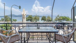 A balcony with a table and chairs, a view of the sea, and a distant mountain. - Room 'Double  Mountain View 1' with Mountain View, Wi-Fi and Air Conditioning (Nikiana)