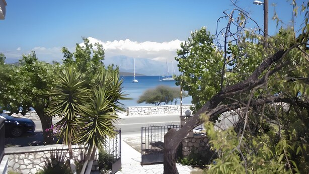 A coastal view with a stone pathway leading to a gate, surrounded by greenery and a clear blue sky. - Room 'Double  Mountain View 1' with Mountain View, Wi-Fi and Air Conditioning (Nikiana)