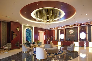 A hotel lobby with a reception desk, seating area, and a large chandelier. - Concorde Creek View Hotel (Dubai)