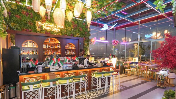 A bar area with a green wall, bar stools, and a neon sign. - Concorde Creek View Hotel (Dubai)