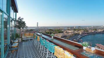 Une terrasse avec des sièges extérieurs, une vue sur la ville et un plan d’eau.