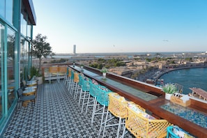 A terrace with outdoor seating, a view of the city, and a body of water. - Concorde Creek View Hotel (Dubai)
