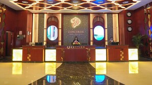 A hotel reception area with a marble floor, a reception desk, and a large logo on the wall. - Concorde Creek View Hotel (Dubai)