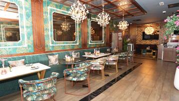 A restaurant with a green upholstered booth seating area, patterned chairs, and chandeliers.
