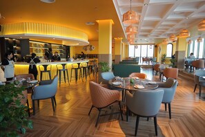 A modern restaurant with a bar area, wooden flooring, and contemporary seating.