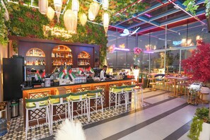 A bar area with a green wall, bar stools, and a neon sign. - Concorde Creek View Hotel (Dubai)