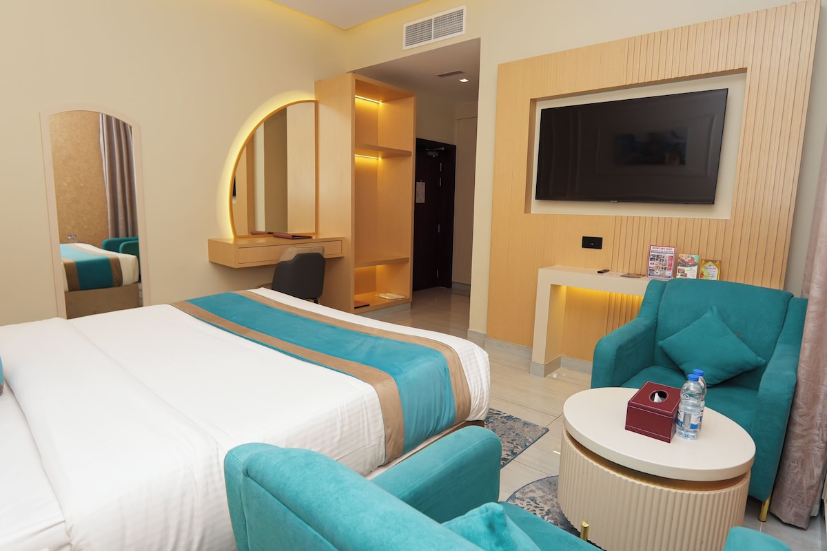 Una habitación de hotel con cama, escritorio, televisión y zona de estar.