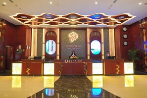 A hotel reception area with a marble floor, a reception desk, and a large logo on the wall. - Concorde Creek View Hotel (Dubai)