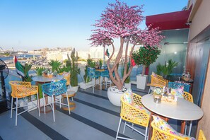 A rooftop terrace with outdoor seating, a decorative tree, and a view of the cityscape. - Concorde Creek View Hotel (Dubai)
