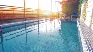 A swimming pool with clear blue water, a sunlit terrace with a railing, and a few lounge chairs. - Concorde Creek View Hotel (Dubai)