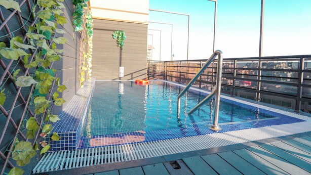 A rooftop pool with a metal ladder, a wooden deck, and a view of the cityscape. - Concorde Creek View Hotel (Dubai)