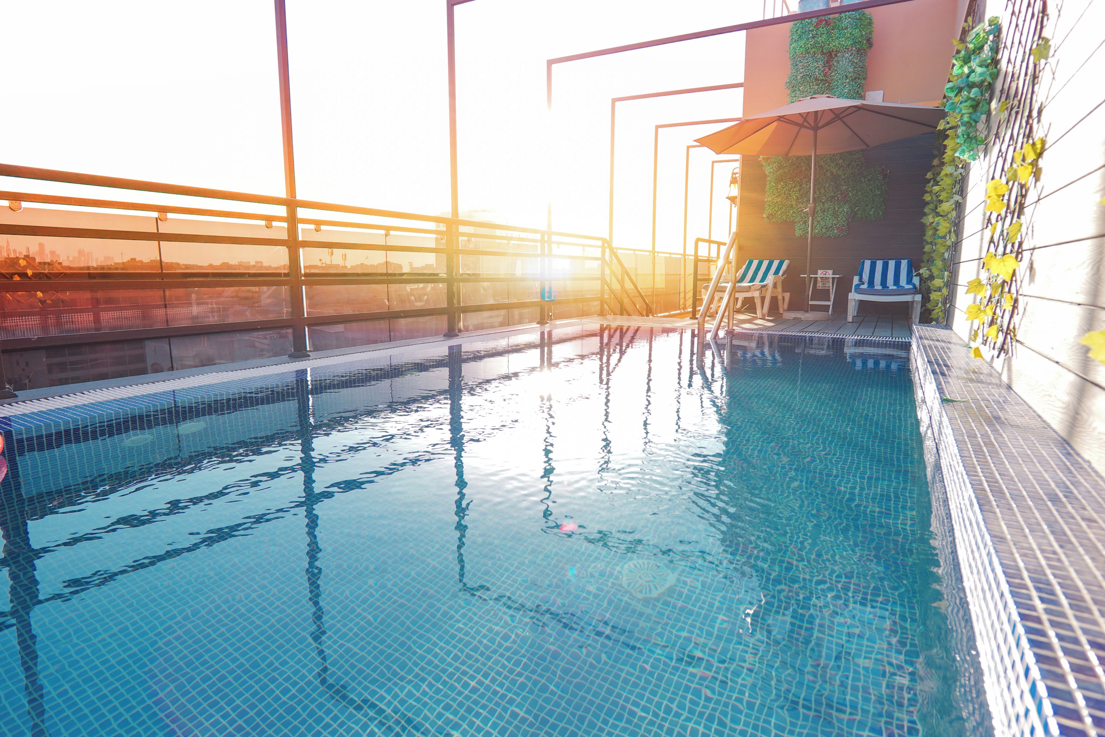 Une piscine à l’eau d’un bleu cristallin, une terrasse ensoleillée avec une balustrade et quelques chaises longues.