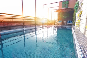 A swimming pool with clear blue water, a sunlit terrace with a railing, and a few lounge chairs. - Concorde Creek View Hotel (Dubai)