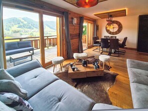 A spacious living room with a large sofa, a coffee table, and a dining area with chairs. - Holy Cow | Design apartment close to the slopes (Les Gets)