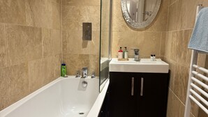 A modern bathroom with a freestanding bathtub, a vanity with a mirror, and a towel rack. - 2 Bed Flat - Sleeps 4 - Parking - Wifi (London)