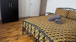 A bedroom with a bed, a wardrobe, and a door. - 2 Bed Flat - Sleeps 4 - Parking - Wifi (London)