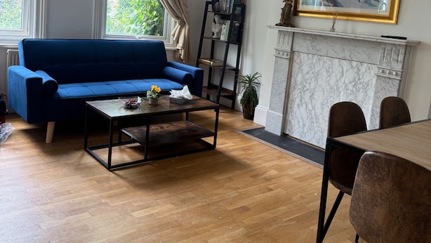 A living room with a blue sofa, wooden coffee table, and a fireplace. - 2 Bed Flat - Sleeps 4 - Parking - Wifi (London)