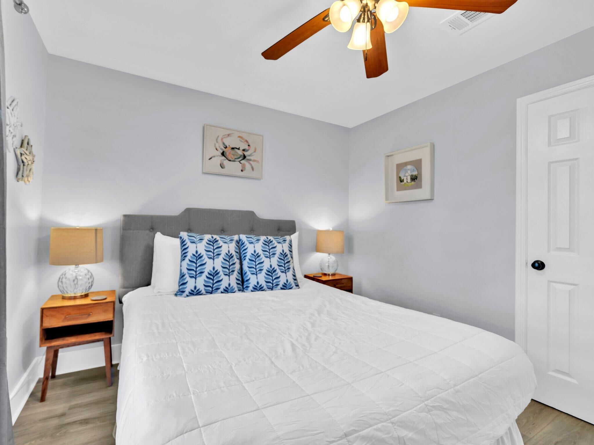Une chambre à coucher comprenant un lit, deux tables de chevet, un ventilateur de plafond et deux lampes fixées au mur.