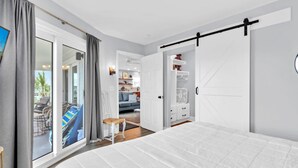 Una camera da letto con un letto grande, una porta scorrevole verso un balcone e vista su un'area living.
