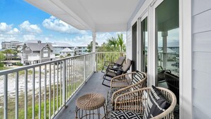 Un balcone con mobili in vimini e vista sulla spiaggia e altri edifici.