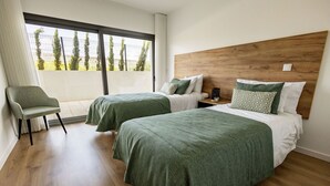 A hotel room with two beds, a chair, a wooden headboard, and a large window with a view of trees. - Sunset Nazaré Apartment - BY SCH (Nazaré)
