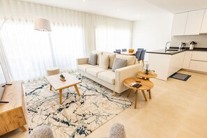 A modern living room with a sofa, coffee table, and a dining area with chairs. - Ocean Sunset Nazaré - BY SCH (Nazaré)