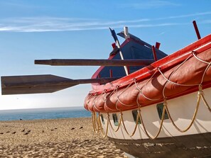 A boat with a red and white hull, wooden oars, and a rope tied to the side.