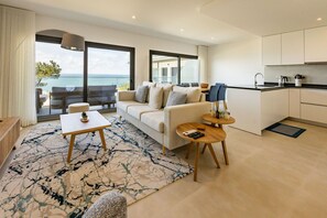 A modern living room with a sofa, coffee table, and a view of the sea.