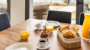 A breakfast table with orange juice, coffee, croissants, and strawberries.