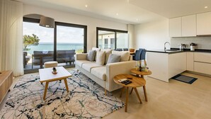 A modern living room with a sofa, coffee table, and a view of the sea.