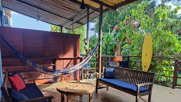 Eine Holzterrasse mit einer Hängematte, einer Bank und einem Tisch.