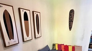 Ein Wohnzimmer mit einer Couch, einem kleinen Holztisch und einer farbenfrohen Bank. An den Wänden hängen gerahmte Bilder.