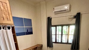 Ein Schlafzimmer mit Bett, Schreibtisch, Stuhl, Kleiderschrank und einem Fenster mit Vorhängen.