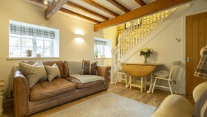 Ein gemütliches Wohnzimmer mit einem braunen Ledersofa, einem Holztisch und einer Treppe mit Holzwandung.