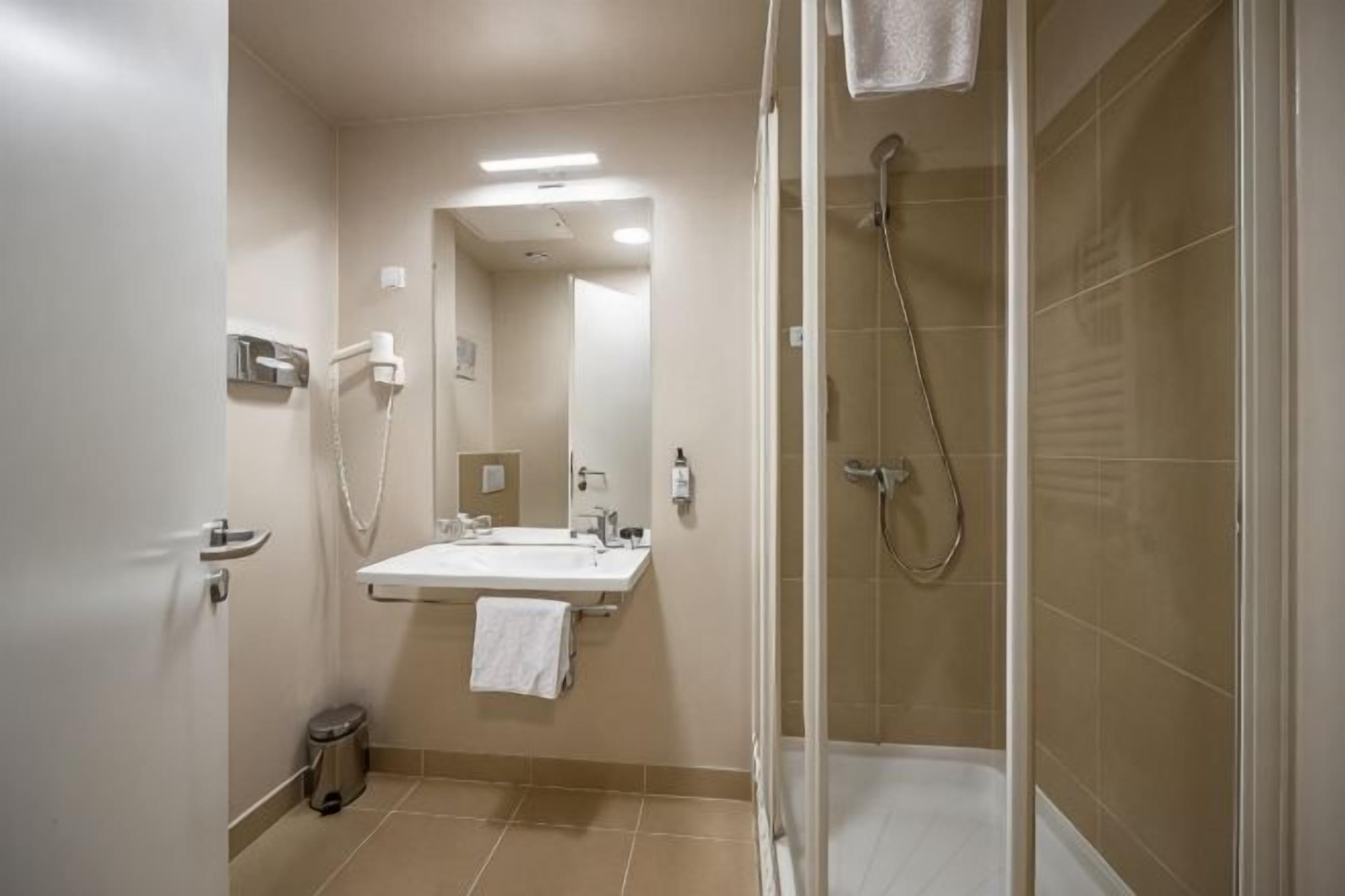 Een badkamer met douche, wastafel en spiegel.