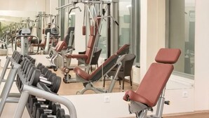 A gym with weight machines, a bench, and a mirror. - Erzsébet Királyné Szálloda (Godollo)
