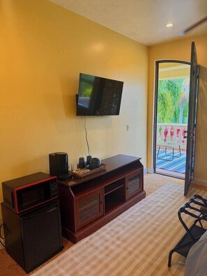 Enjoy a comfortable stay in this stylish room featuring a flat-screen TV, small refrigerator, and sliding glass door leading to a balcony with outdoor seating.