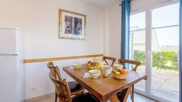 Comedor con una mesa de madera dispuesta para el desayuno, con pan, fruta y un tazón de cereal.