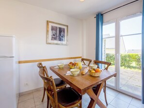 Comedor con una mesa de madera dispuesta para el desayuno, con pan, fruta y un tazón de cereal.
