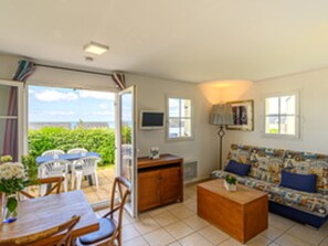 Una habitación con sofá, una mesa, sillas y vistas al exterior.