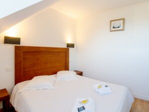 A bedroom with a wooden headboard, a single bed, a nightstand, and a wall-mounted light fixture.