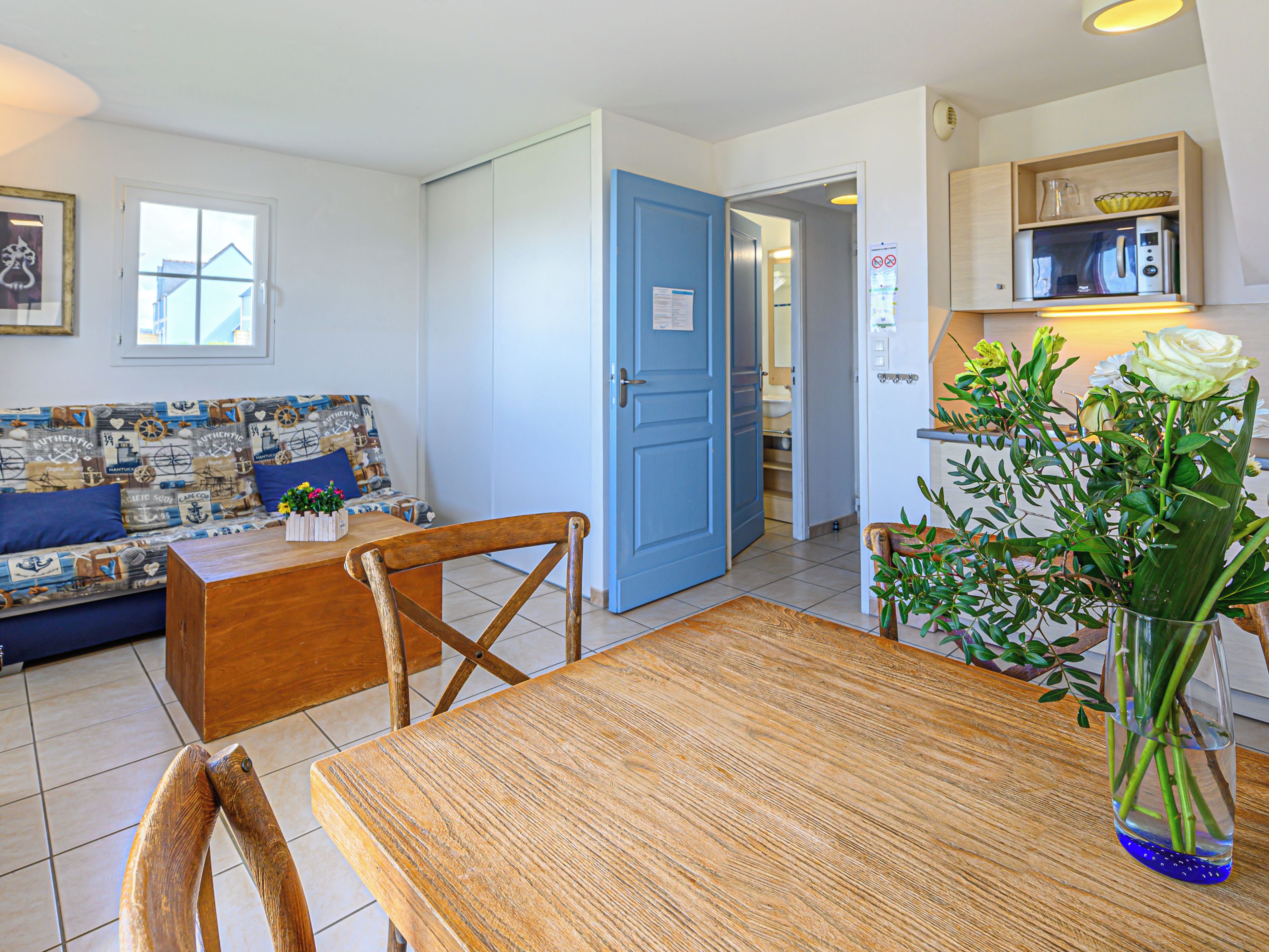 Un salon chaleureux avec une porte bleue, une table à manger et un canapé aux motifs marins.