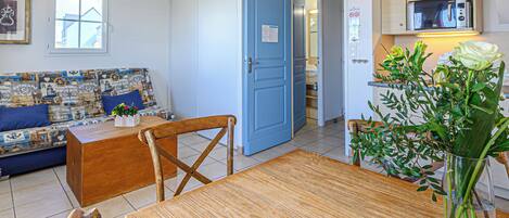 Un salon chaleureux avec une porte bleue, une table à manger et un canapé aux motifs marins.