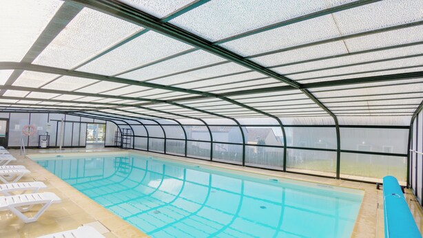 An indoor swimming pool with clear lanes, a lifeguard stand, and lounge chairs along the side. - Residence Vacanceole Les Terrasses De Pentrez (Saint-Nic)