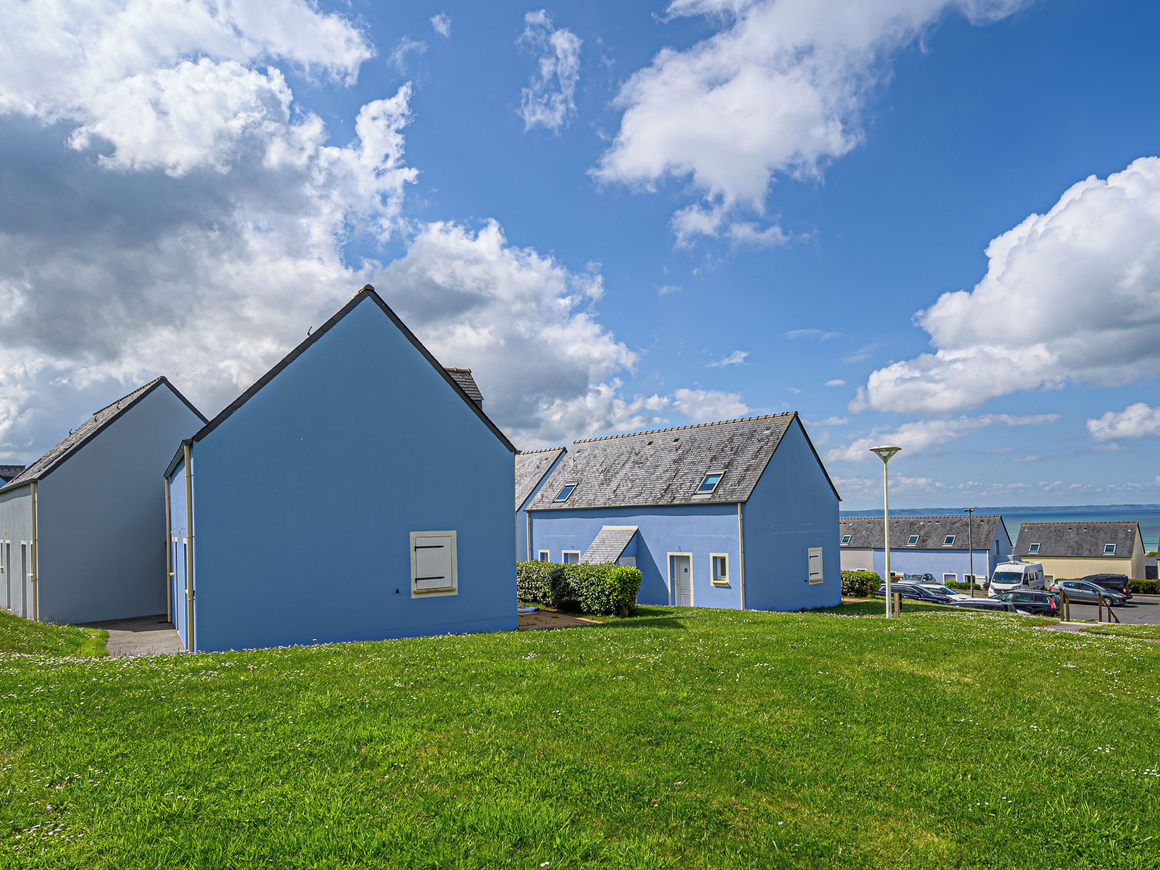 A row of blue houses with a grassy lawn in front.