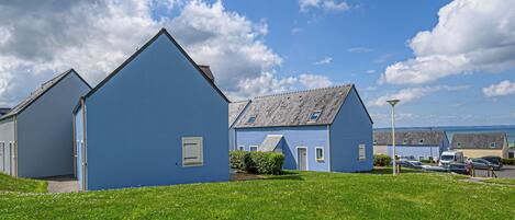 A row of blue houses with a grassy lawn in front.