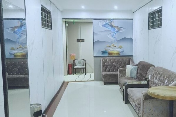 A hotel lobby with a reception desk, two sofas, a small table, and artwork on the walls.